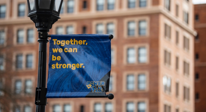 Image of banner reading "Together we can be stronger" in front of campus building